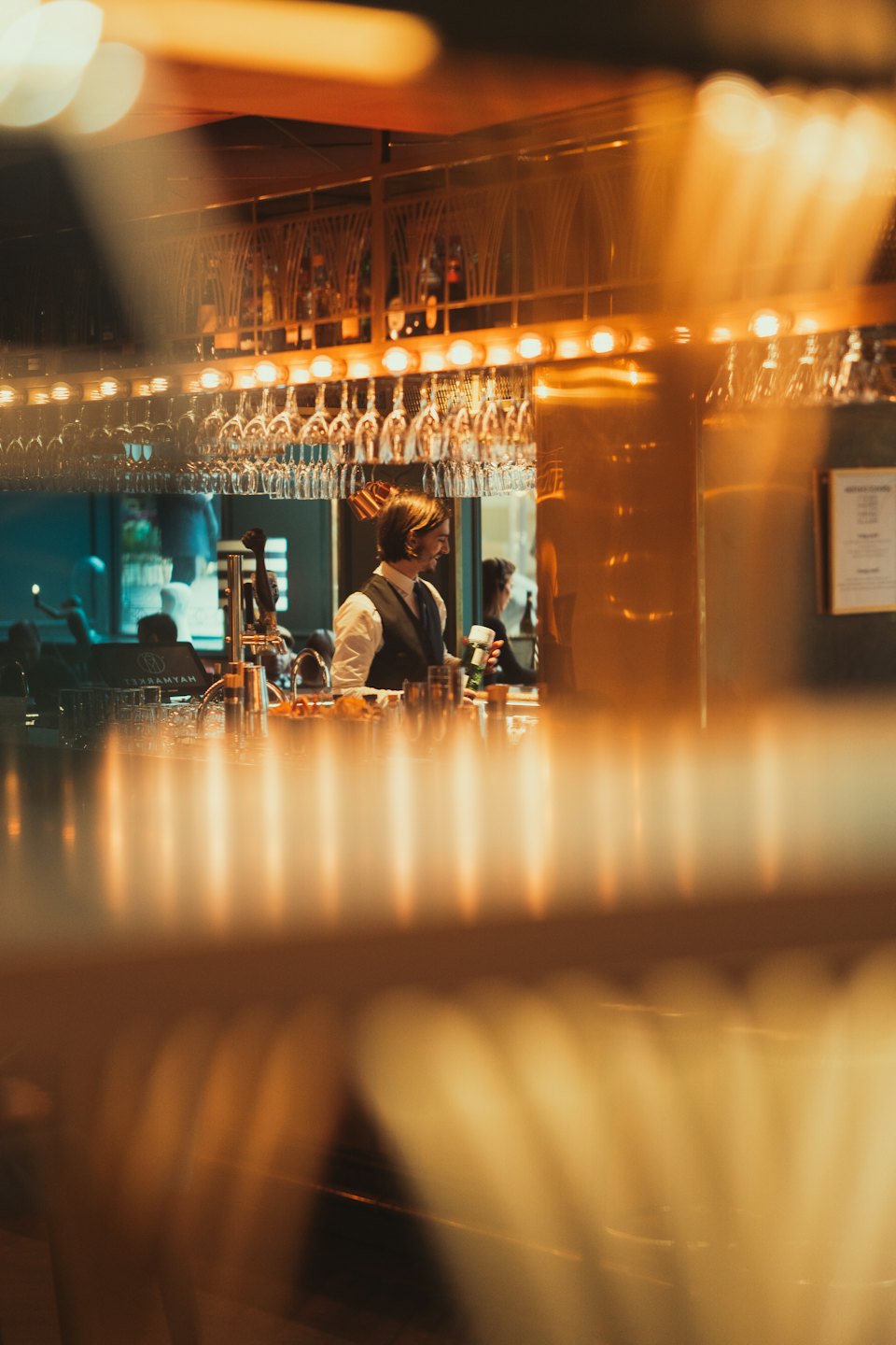 A bartender shakes a metal cocktail shaker behind a bar.