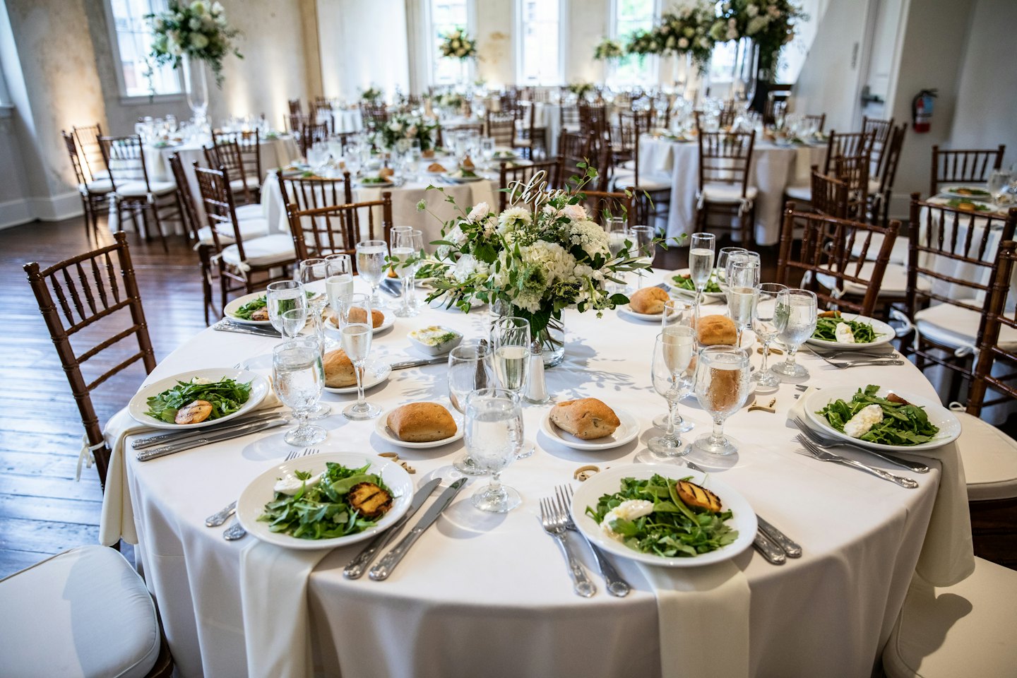 Formal event tables set with white linens and floral centerpieces.