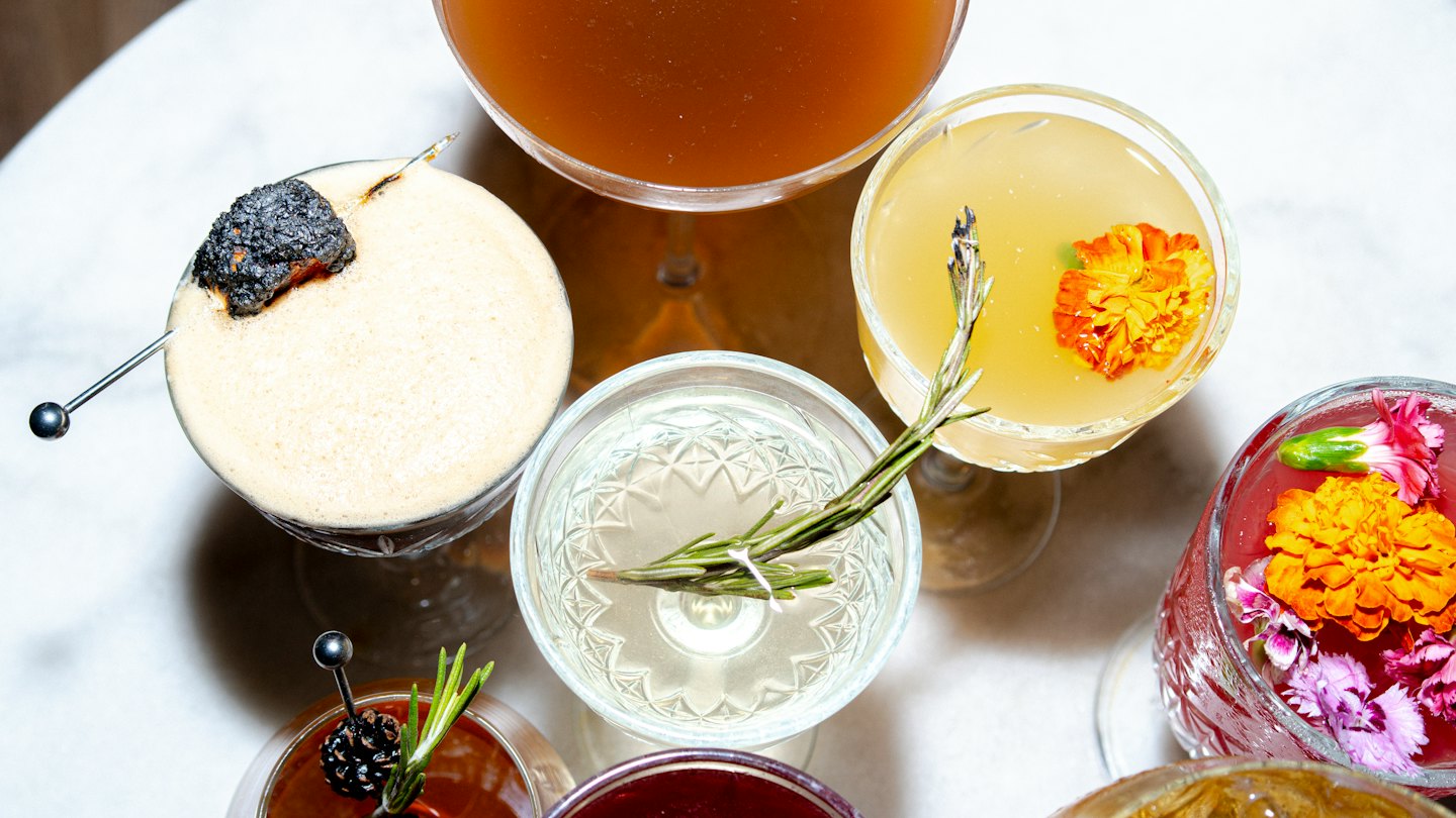 Several garnished cocktails arranged on a white marble surface.